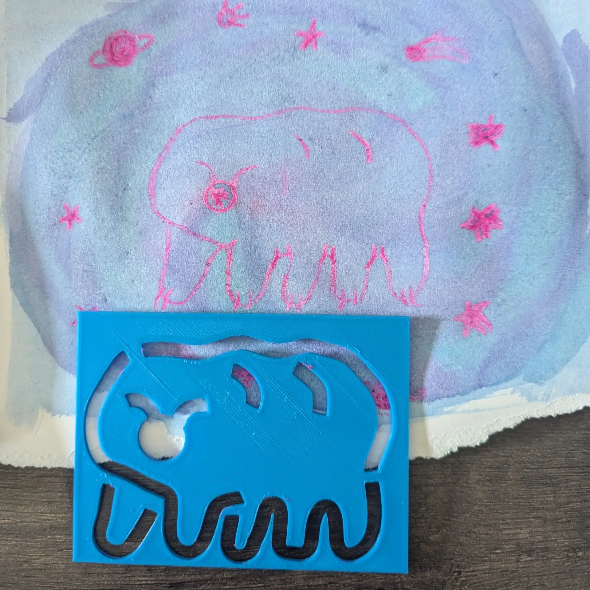 3D-printed tardigrade stencil in front of a wax-resist watercolor.